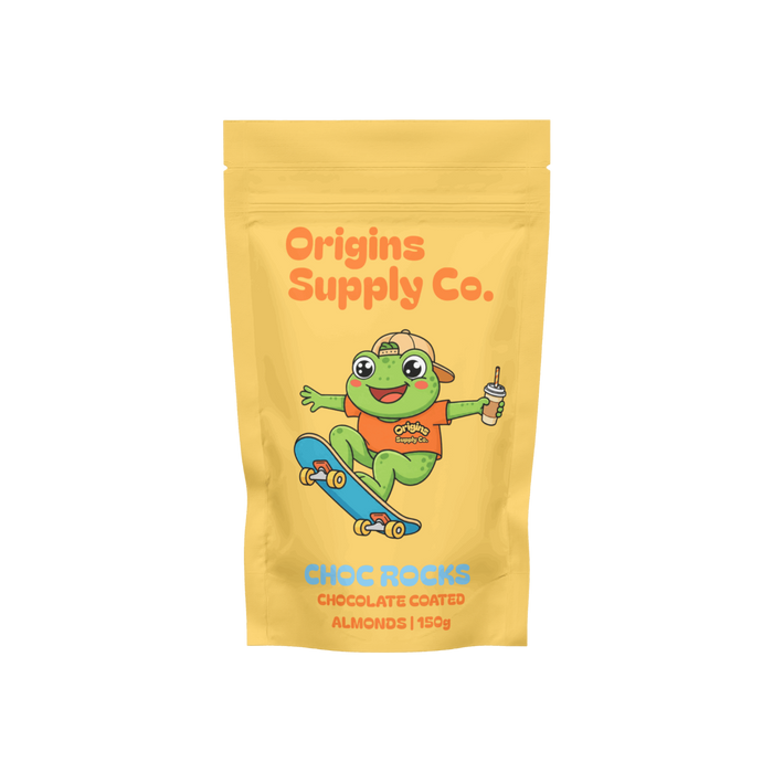 A yellow stand-up pouch of Origins Supply Co. Choc Rocks chocolate coated almonds, featuring a cartoon green frog character on a skateboard with an orange shirt and a blue skateboard.
