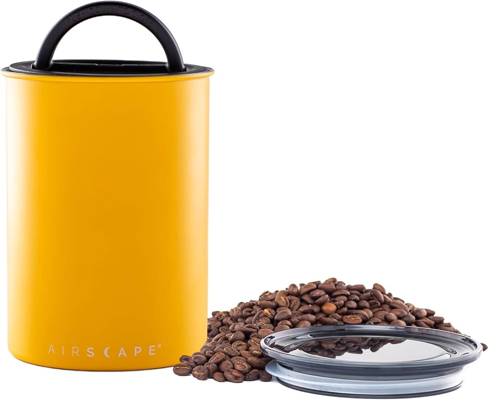 Yellow air-tight container with coffee beans and a clear lid on a white background